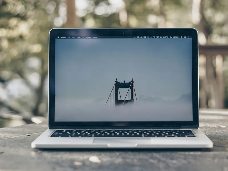 Un ordinateur portable ouvert sur un logiciel de mise en page, posé sur un bureau gris